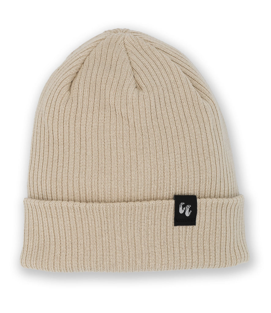 A pale beige knitted beanie hat laid down flat with the photo taken from above. The hat is made from Organic Cotton and has a small, black, fabric label stitched to the top of the cuff. The label has a graphic of two hands, the Crimp'd Clothing logo in white