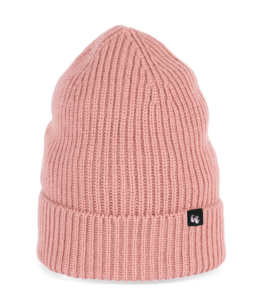 A soft pink beanie with chunky, fisherman-style ribbed knit. It has a black fabric label with a white logo stitched to the cuff