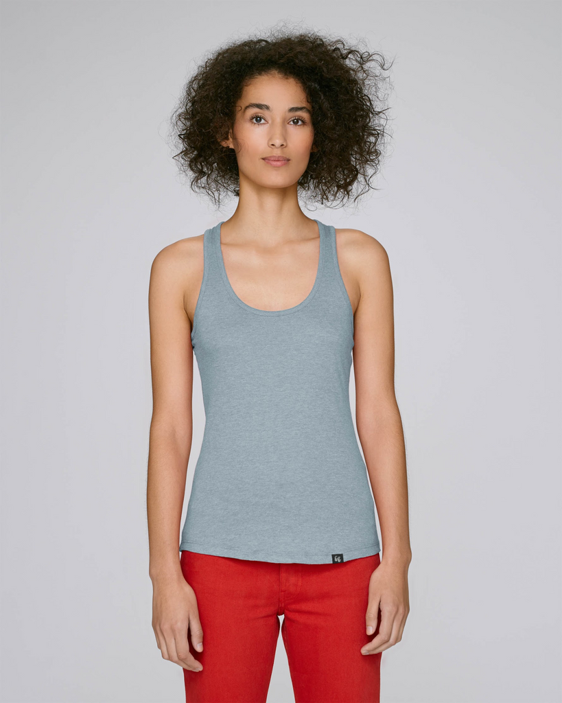 A woman wearing an organic cotton racer back tank top in heather ice blue with a small black logo on the back at the top
