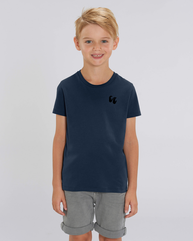 A girl wearing a kids organic cotton t-shirt in french navy blue, with a printed black left chest logo