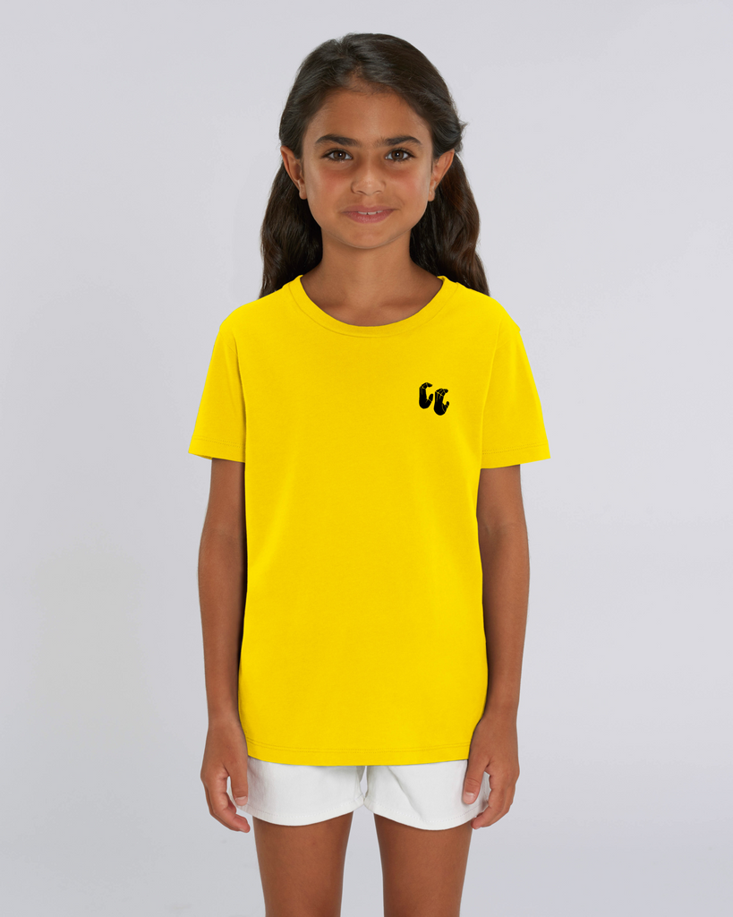 A girl wearing a kids organic cotton tshirt in golden yellow, with a printed black left chest logo