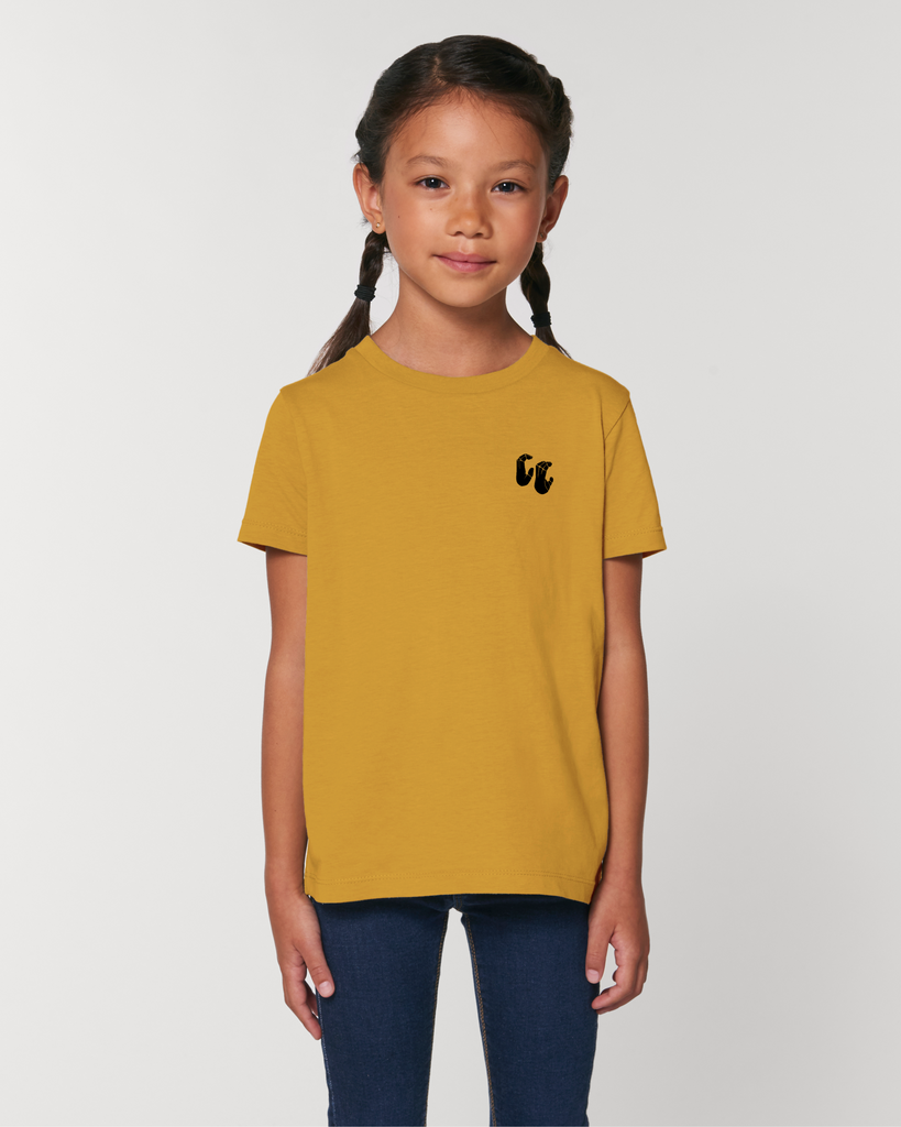 A girl wearing an organic cotton kids t-shirt in ochre yellow, with a printed black left chest logo