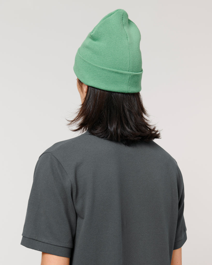 The rear-view of a person wearing a dusty mint green beanie hat and grey t-shirt