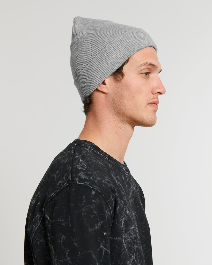 The side-view of a person wearing a mid-grey beanie hat and black t-shirt