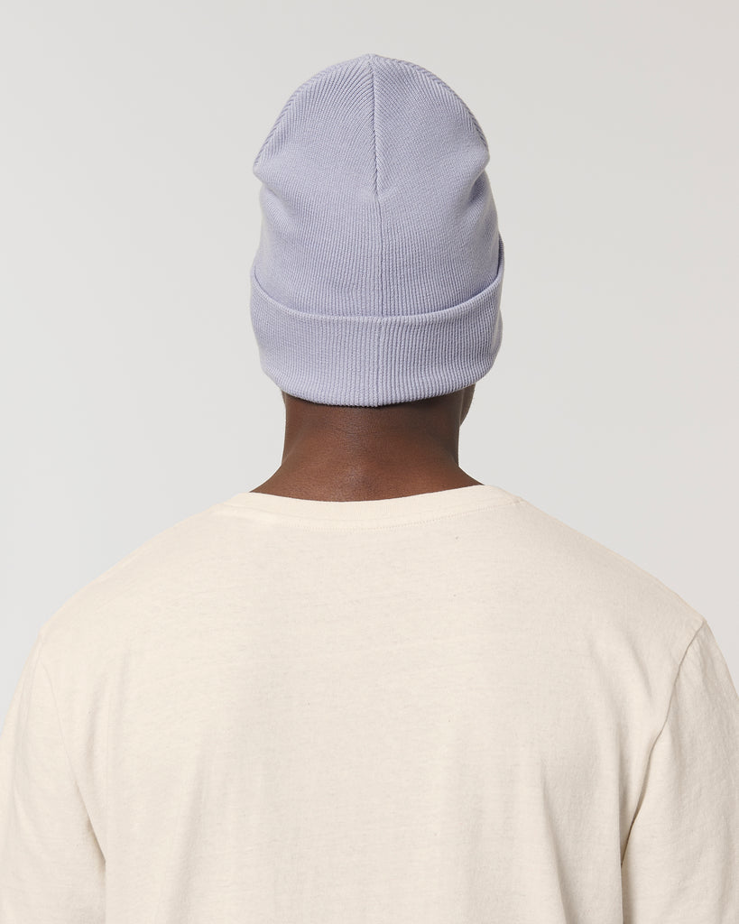 The rear-view of a person wearing a pastel lavender purple beanie hat and cream t-shirt