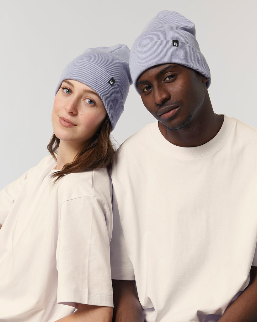 Two people stood together wearing lavender purple beanie hats, with baggy cream t-shirts