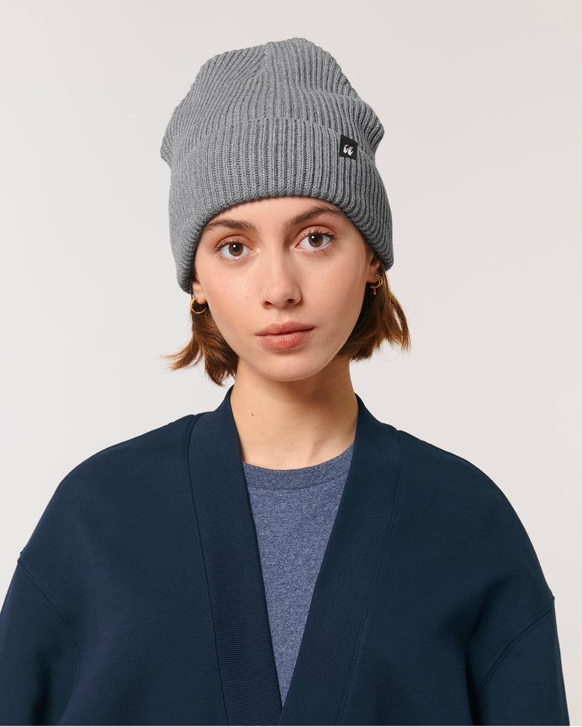 A woman wearing a mid heather grey unisex fisherman's beanie hat made from organic cotton